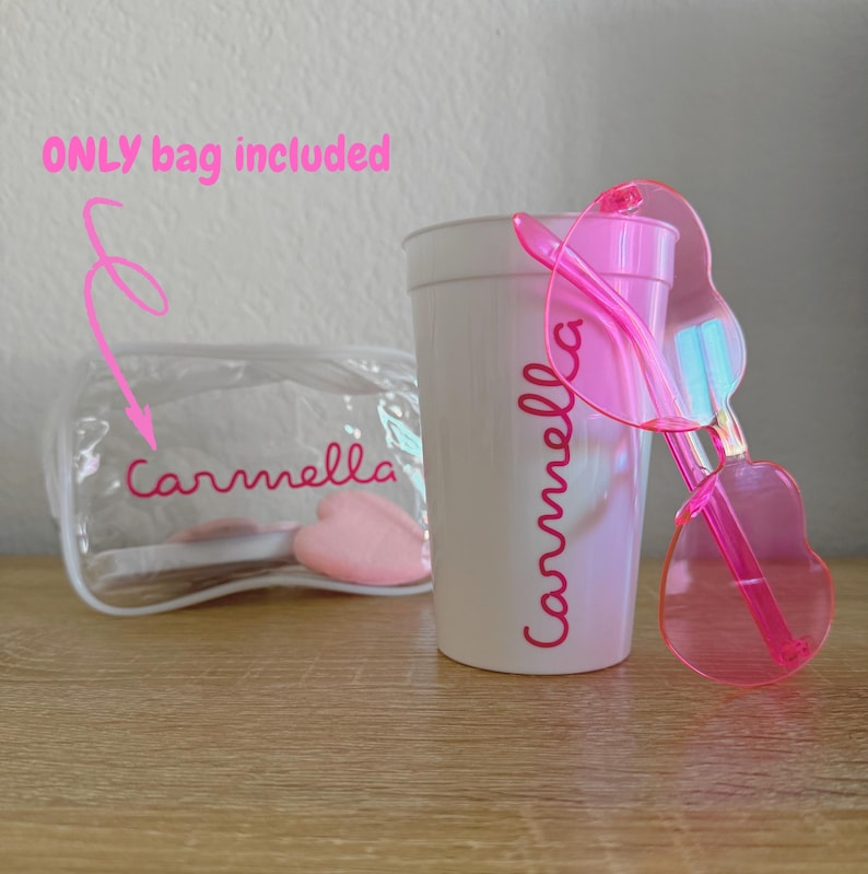 May include: A clear plastic zippered pouch with the name Carmella printed in pink, a white plastic cup featuring the name Carmella in pink script, and a pair of translucent pink heart-shaped sunglasses. The text ONLY bag included is visible.