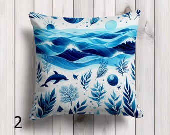 Puede incluir: Cojín cuadrado con un diseño de océano azul y blanco. El cojín presenta olas estilizadas, un delfín y varias plantas acuáticas. La paleta de colores incluye tonos de azul y blanco, creando una estética costera.
