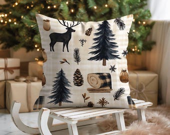 May include: A cushion with a winter theme. It has a cream plaid background with illustrations of a black deer, pine trees, pine cones, and a rolled blanket. The cushion is placed on a white sled, evoking a festive atmosphere.
