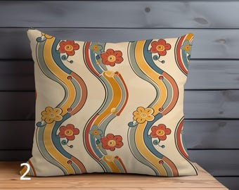 May include: Square throw pillow with a retro floral pattern. The design features wavy stripes in yellow, blue, and orange, with red and yellow flowers. The pillow is on a wooden surface.