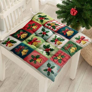 Könnte beinhalten: Ein quadratisches Weihnachts-Stuhlkissen mit Patchwork-Design. Jedes Quadrat zeigt festliche Elemente wie goldene Glocken, rote Schleifen, Stechpalmen und Karomuster in Rot, Grün und Blau. Das Kissen liegt auf einem weißen Stuhl.