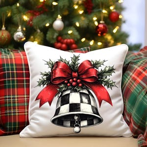 May include: White square pillow with a black and white checkered bell design, a red bow, and holly accents. The pillow is placed on a chair with red and green plaid pillows and a Christmas tree in the background.
