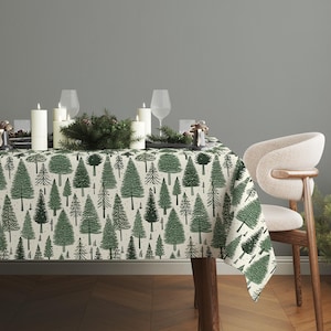 May include: A cream-colored tablecloth with a repeating pattern of green Christmas trees. The table is set with white candles, wine glasses, and decorative greenery, creating a festive holiday scene.