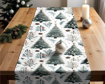 Puede incluir: Un camino de mesa navideño blanco con un patrón repetido de árboles de Navidad, piñas y ramitas de acuarela. El camino de mesa se muestra sobre una mesa de madera con una vela encendida y adornos.