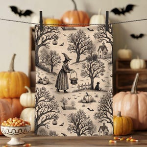 Puede incluir: Un panel de tela con temática de Halloween con una ilustración en blanco y negro de una bruja, calabazas, árboles y un gato negro. El panel está colgado con una pinza. Las calabazas y los caramelos de maíz están en primer plano.
