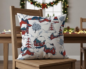 May include: A decorative pillow with a winter scene design. The pillow features a repeating pattern of red cabins, snow-covered trees, and mountains in shades of red, blue, and white. The pillow is placed on a wooden chair.