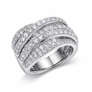 May include: A wide, silver-toned ring with multiple curved bands, each encrusted with numerous small, sparkling clear gemstones. The ring has a modern, elegant design, with a polished finish.