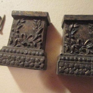 May include: Two antique metal curtain tiebacks with a decorative floral design and a beaded trim.