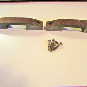 May include: Two dark brown wooden cabinet handles with a rectangular shape and a recessed grip area. Four silver screws are included for installation. The handles are designed for furniture or cabinet doors.