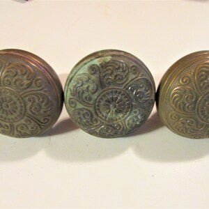 May include: Three antique brass door knobs with intricate floral designs.