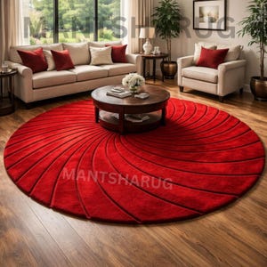 May include: A large circular rug in a vibrant red color featuring a textured spiral pattern of carved grooves radiating from the center. The rug is positioned on a wooden floor and displays the text MANTSHARUG printed across its surface.