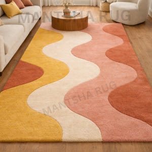 May include: A rectangular rug with a wavy pattern in yellow, cream, peach, and rust. The rug is made of a soft material and is placed on a wooden floor. The design is reminiscent of a retro style.