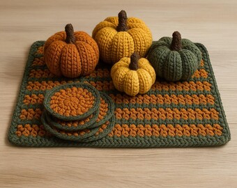 May include: A collection of handmade crochet pumpkins in various sizes and colors, including orange, yellow, and green, with brown stems. The pumpkins are arranged on a matching green and orange striped crochet placemat, with a set of matching coasters.