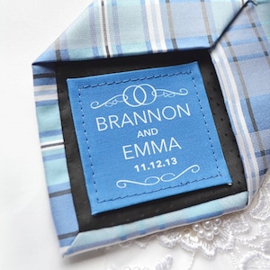 May include: A blue and white plaid tie with a blue label that says "Brannon and Emma 11.12.13" in white text.