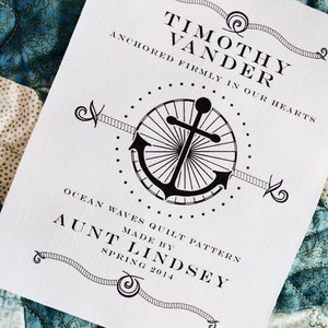 May include: A white card with black text and an anchor graphic. The text reads "Timothy Vander Anchored firmly in our hearts Ocean Waves Quilt Pattern Made by Aunt Lindsey Spring 2014".