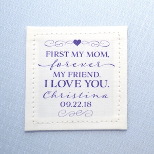 May include: White fabric square with a purple stitched border and text that reads "First my mom, forever my friend. I love you. Christina 09.22.18".