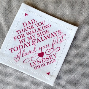 May include: White fabric square with pink stitching and pink text that reads "DAD, THANK YOU FOR WALKING BY MY SIDE TODAY & ALWAYS. I loved you first. LYNDSEY 09.19.2019".