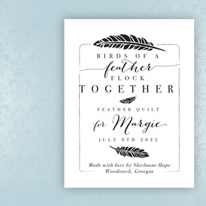 May include: A white card with black text and a feather design. The text reads "Birds of a feather flock together, Feather Quilt for Margie, July 8th 2022, Made with love by Shirlanne Hope, Woodstock, Georgia".