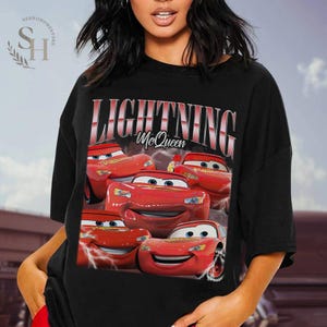 Puede incluir: Camiseta negra con un gr&aacute;fico de Rayo McQueen de la pel&iacute;cula Cars. El dise&ntilde;o incluye m&uacute;ltiples im&aacute;genes del coche de carreras rojo con el texto "LIGHTNING McQueen" en fuente roja y blanca.