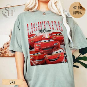 Puede incluir: Camiseta verde claro con un dise&ntilde;o de Rayo McQueen de la pel&iacute;cula Cars. El dise&ntilde;o incluye el texto "LIGHTNING McQueen" en rojo y varias im&aacute;genes del coche de carreras rojo. La camiseta tiene mangas cortas.
