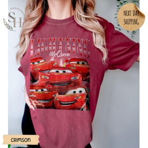 Puede incluir: Camiseta de color carmes&iacute; con un dise&ntilde;o de Rayo McQueen de la pel&iacute;cula Cars. El dise&ntilde;o incluye el texto "LIGHTNING McQueen" y varias im&aacute;genes del personaje. Esta camiseta informal es una prenda c&oacute;moda.