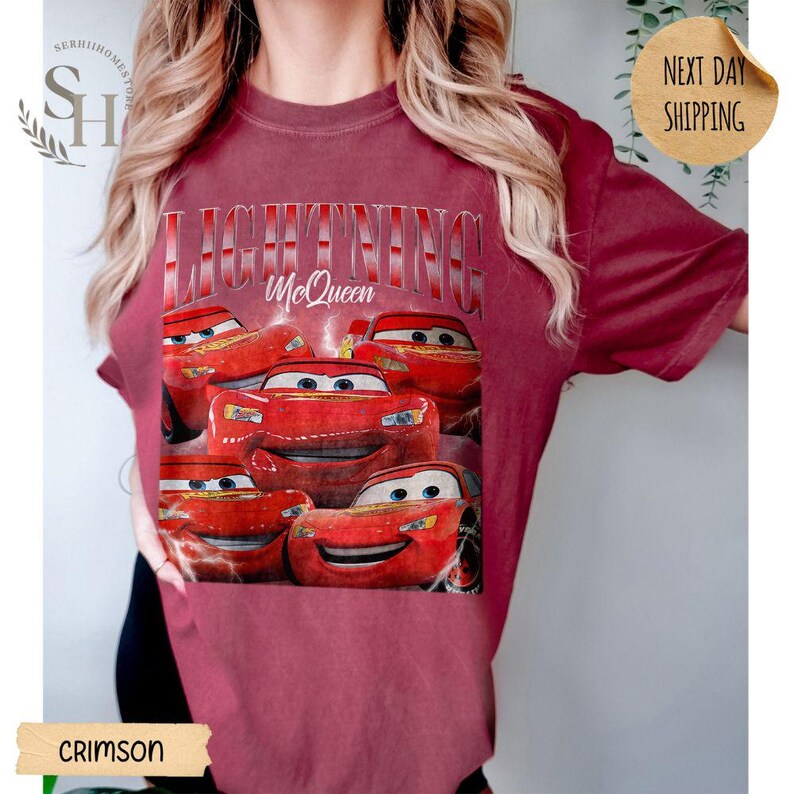 Puede incluir: Camiseta de color carmes&iacute; con un dise&ntilde;o de Rayo McQueen de la pel&iacute;cula Cars. El dise&ntilde;o incluye el texto "LIGHTNING McQueen" y varias im&aacute;genes del personaje. Esta camiseta informal es una prenda c&oacute;moda.