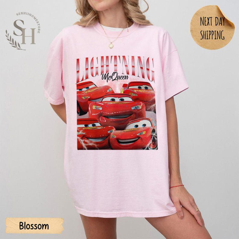 Puede incluir: Camiseta rosa claro con un dise&ntilde;o de Rayo McQueen de la pel&iacute;cula Cars. El dise&ntilde;o incluye el texto "LIGHTNING McQueen" en rojo. La camiseta tiene un corte holgado y extragrande.