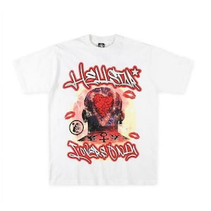 May include: White t-shirt featuring a graphic design with the text "HELLSTAR" in red and black graffiti-style lettering. The design includes a heart-shaped image on a person's head, surrounded by red lips and the words "LOVERS ONLY".