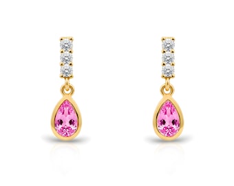 May include: A pair of gold drop earrings. Each earring has a vertical bar with three small, clear stones, connected to a teardrop-shaped pink gemstone. The earrings are set against a white background.