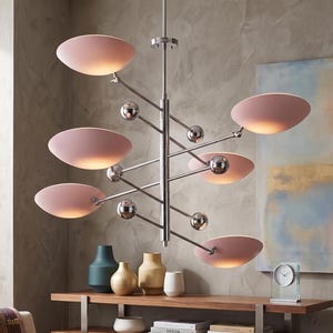 May include: A modern chandelier with a chrome finish and eight pink, saucer-shaped light fixtures. The light fixtures are arranged on a central vertical rod with spherical accents. The chandelier hangs above a wooden shelf with decorative vases.