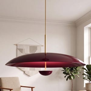 May include: A pendant light fixture featuring a large, glossy, deep burgundy saucer-shaped shade suspended by a slender brass-colored rod. A smaller, matching burgundy bowl-shaped component is attached to the center underside of the main shade.
