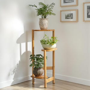 May include: A three-tiered bamboo plant stand with three potted plants. The stand has a natural wood finish and a simple design. The plants are green, and the pots are ceramic. The stand is approximately 90 cm tall.