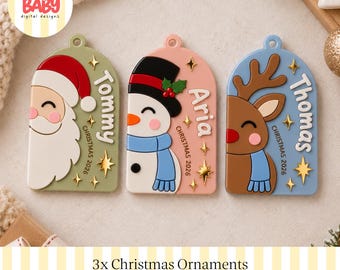 Könnte beinhalten: Drei bogenförmige Weihnachtsschmuck-Anhänger mit einem Weihnachtsmann, einem Schneemann und einem Rentier. Jeder Anhänger ist mit den Namen Tommy, Aria und Thomas, dem Text Christmas 2026 und kleinen goldenen Sternen versehen.