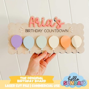 Puede incluir: Un tablero de cuenta regresiva de cumpleaños de madera con el nombre "Aria's" en letras rosas. El tablero presenta seis recortes de globos de colores pastel y el texto "BIRTHDAY COUNTDOWN". El tablero está sostenido por una mano. La parte inferior del tablero tiene el texto "THE ORIGINAL BIRTHDAY BOARD".