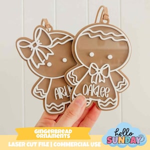 Pode incluir: Dois enfeites de homem de gengibre com contornos brancos e laços. Um enfeite diz "Arly" e o outro "Oaklee". Os enfeites são segurados em frente a um fundo branco. A imagem também inclui o texto "GINGERBREAD ORNAMENTS" e "hello SUNDAY".