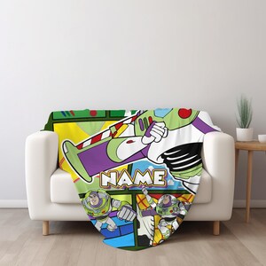 Puede incluir: Una manta de forro polar suave con un estampado gr&aacute;fico colorido del personaje Buzz Lightyear en varias poses de acci&oacute;n. El dise&ntilde;o incluye un esquema de colores amarillo, blanco y morado con la palabra NAME impresa en letras blancas.