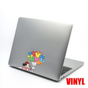 May include: A gray laptop with a colorful sticker of Mickey Mouse holding a bouquet of Mickey Mouse-shaped balloons. The balloons are red, yellow, green, blue, and orange. The word "VINYL" is printed in red.