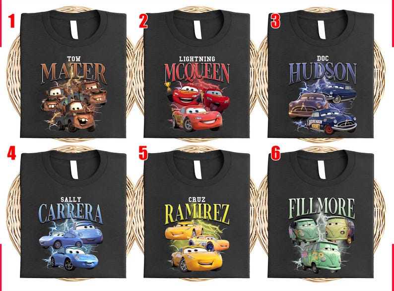 May include: Six black t-shirts featuring characters from the film "Cars." Each shirt displays a different character's name and image: Mater, Lightning McQueen, Doc Hudson, Sally Carrera, Cruz Ramirez, and Fillmore.