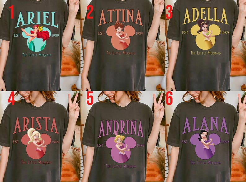 Puede incluir: Camisetas de color gris oscuro con personajes de "La Sirenita". Cada camiseta muestra un nombre en una fuente estilizada sobre un gr&aacute;fico en forma de Mickey Mouse con una ilustraci&oacute;n de personaje y el texto "EST. 1989 The Little Mermaid."