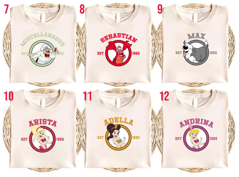 Puede incluir: Camisetas de color crema con varios dise&ntilde;os de personajes de dibujos animados. Cada camiseta presenta el nombre de un personaje diferente en un c&iacute;rculo, junto con el a&ntilde;o "1989". Los dise&ntilde;os incluyen "Miscellaneous", "Sebastian", "Max", "Arista", "Adella" y "Andrina".