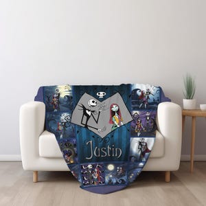 May include: A blue and black patterned throw blanket featuring a collage of scenes with Jack Skellington and Sally from The Nightmare Before Christmas. The center displays a heart-shaped graphic with the characters and the name Justin printed below.