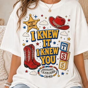 May include: A white t-shirt featuring a graphic print with a yellow sheriff star labeled INFINITY AND BEYOND, a red cowboy hat, red cowboy boots, a stack of blocks labeled T, S, 5, and a beaded necklace with the text YOU'VE GOT A FRIEND IN ME.