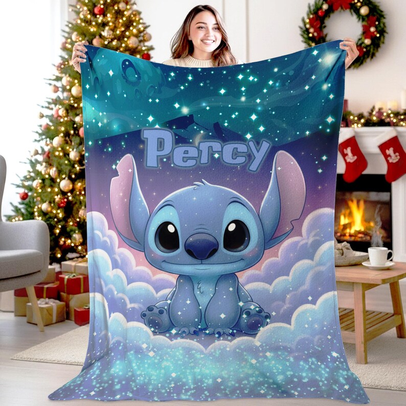 Puede incluir: Una manta de forro polar suave con un personaje alien&iacute;gena azul sentado sobre nubes blancas esponjosas contra un cielo nocturno estrellado azul oscuro. El nombre Percy est&aacute; impreso en letras grandes de color azul claro sobre el personaje.