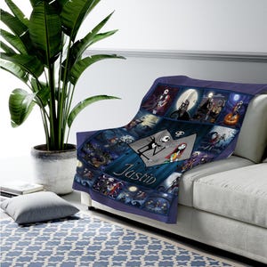 May include: A dark blue fleece throw blanket featuring a collage of scenes from The Nightmare Before Christmas, including Jack Skellington and Sally. The center displays a diamond-shaped graphic with the name Justin printed in white script lettering.