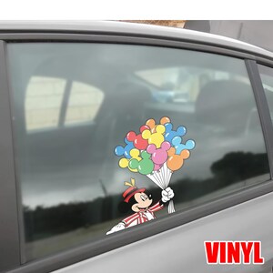 May include: A colorful vinyl decal featuring Mickey Mouse holding a bouquet of Mickey Mouse-shaped balloons. Mickey is dressed in a red and white striped outfit with a matching hat. The balloons are various colors, including red, yellow, blue, pink, and orange. The word "VINYL" is in red.