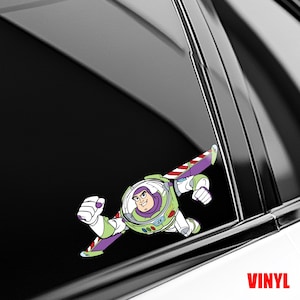 May include: A vinyl decal featuring a cartoon space ranger character in a white, green, and purple suit with extended wings, depicted in a flying pose. The character has a clear helmet dome, a purple hood, and is shown against a dark background.