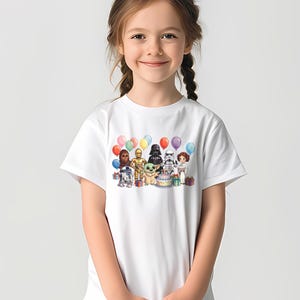 K&ouml;nnte beinhalten: Wei&szlig;es T-Shirt mit einem farbenfrohen Aufdruck von Star Wars-Charakteren, darunter Chewbacca, C-3PO, Darth Vader und Baby Yoda, mit Luftballons und einer Geburtstagstorte. Das Design befindet sich auf der Vorderseite.