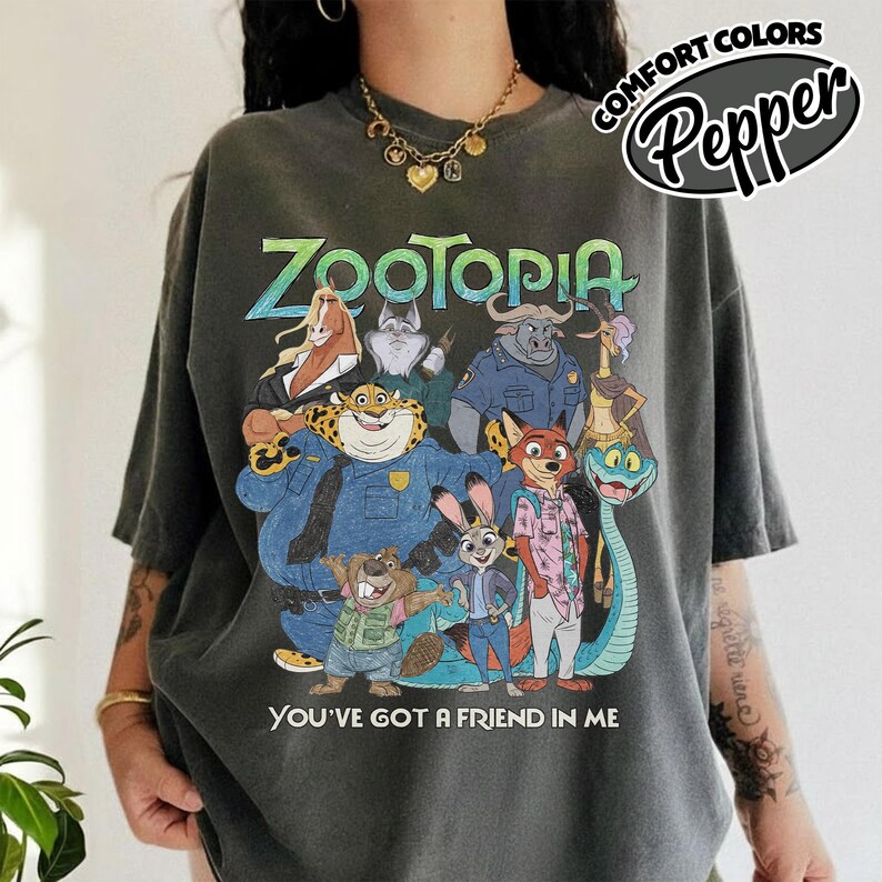 May include: Dark gray t-shirt featuring a colorful graphic of characters from the animated movie "Zootopia." The design includes the movie title and the phrase "You've Got a Friend in Me."