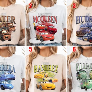 May include: Six t-shirts showcasing characters from the animated film "Cars." Each shirt has a different character's name in a retro font, accompanied by an image of the character. The shirts are in various colours, including white and beige.
