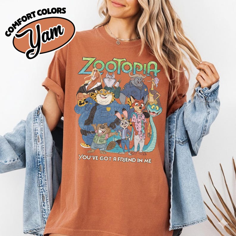May include: A rust-colored t-shirt featuring a graphic of characters from the animated film "Zootopia." The design includes the film's title in green and blue, along with the phrase "You've Got a Friend in Me."